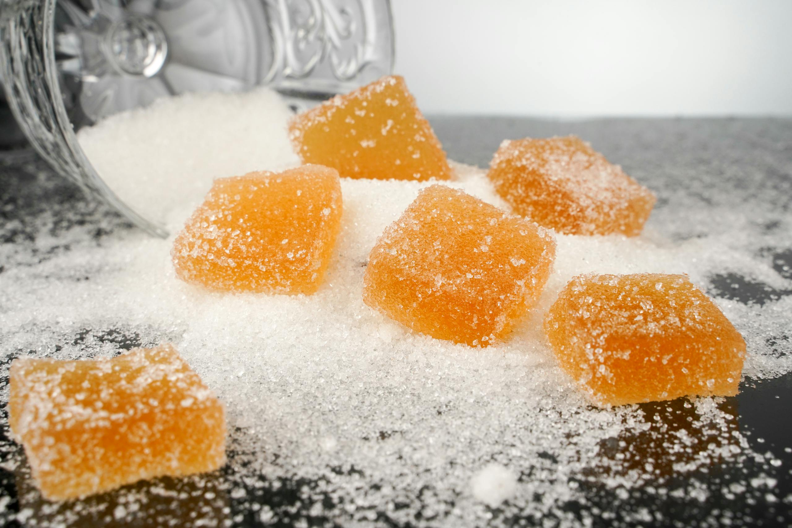 Close-up view of sugar-coated orange gummy candies spilled on a surface.